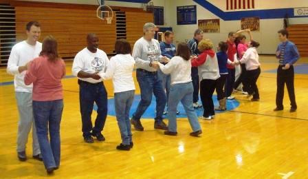 People dancing in pairs inside a gymnasium.