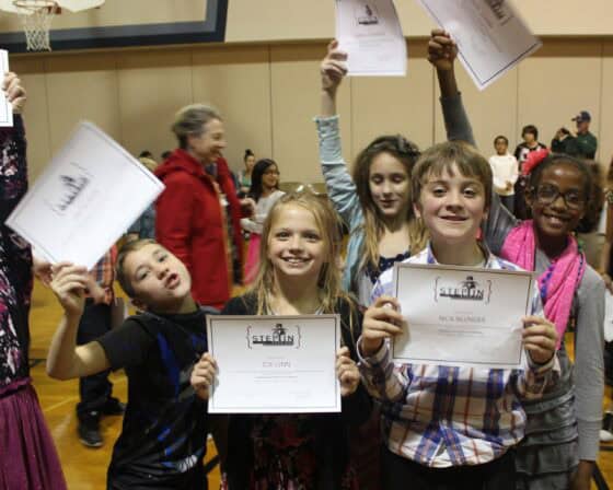 Children proudly holding certificates at a group event.