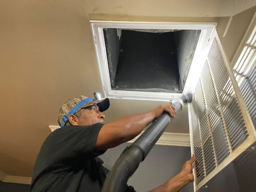 Our technician cleaning an air duct opening with a vacuum brush